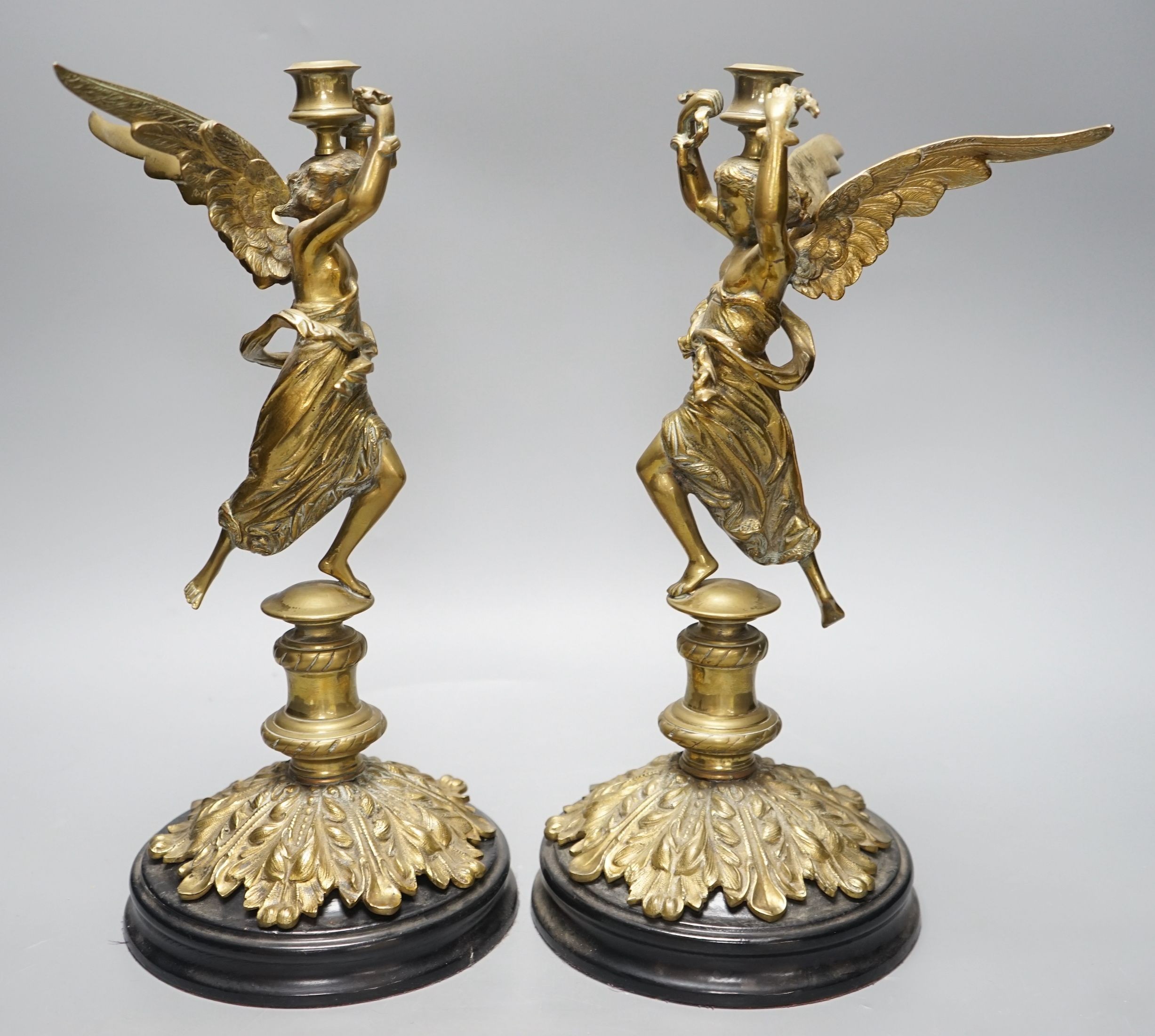 A pair of early 20th century cast brass ‘angel’ candlesticks, 36cms high